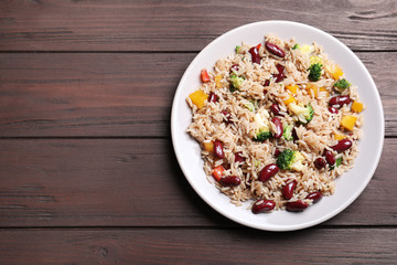 Delicious rice with beans on wooden table, top view. Space for text