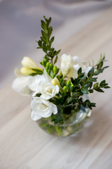 white freesia flowers in a spherical glass vase