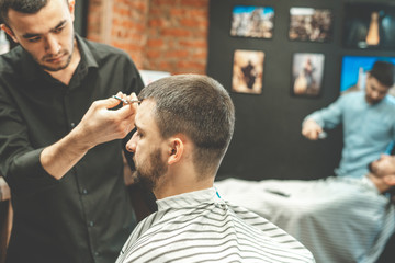 Haircut at the hairdresser. Barber cuts the hair on the client's head. The process of creating...