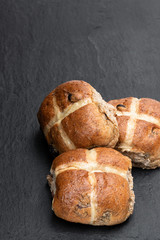 Easter wholemeal hot cross buns on wooden board on black stone background