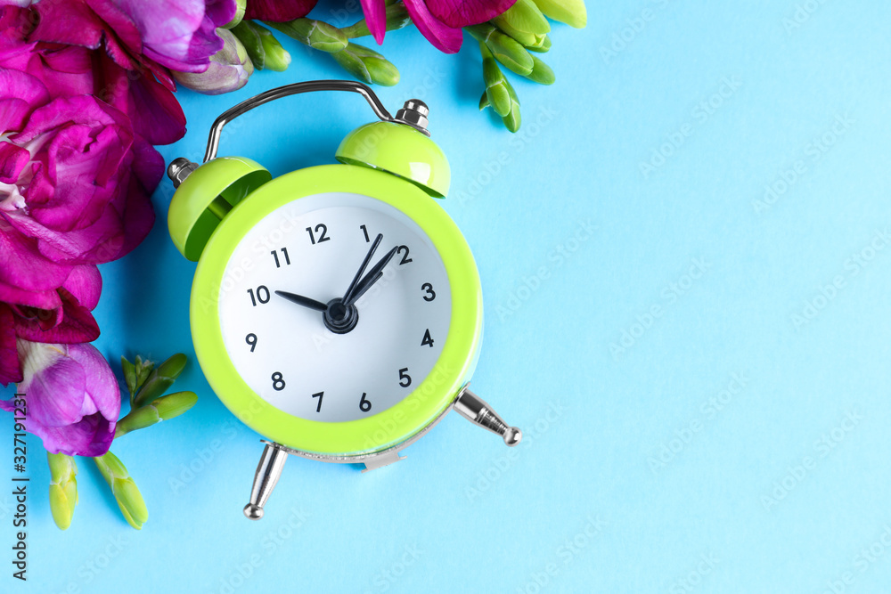 Aufkleber green alarm clock with spring flowers and space for text on light blue background, flat lay. time ch