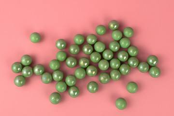 Green pastel marbles at soft pink background. Creative minimal concept.