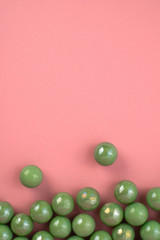 Green pastel marbles at soft pink background. Creative minimal concept.