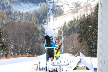 Couple using chairlift at mountain ski resort. Winter vacation