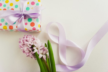 Hyacinth, ribbon and a wrapped gift for International Women's Day. Close up photo.
