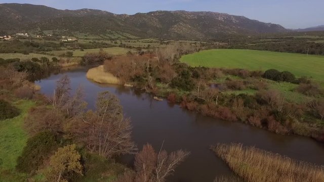 aerial view of the overflight of the lake and coghinas river in sardinia wrapped in trees and agricultural fields with the drone