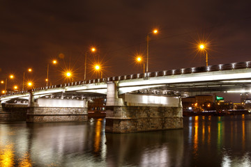 Fototapeta na wymiar Novospassky bridge at night, white lighting of the arches, the bright glare of the sodium lamps of street lights.