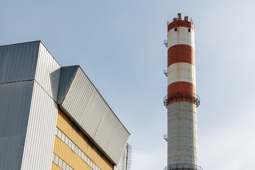 Building of the incinerator and the pipe against the sky, a sunny day. - obrazy, fototapety, plakaty