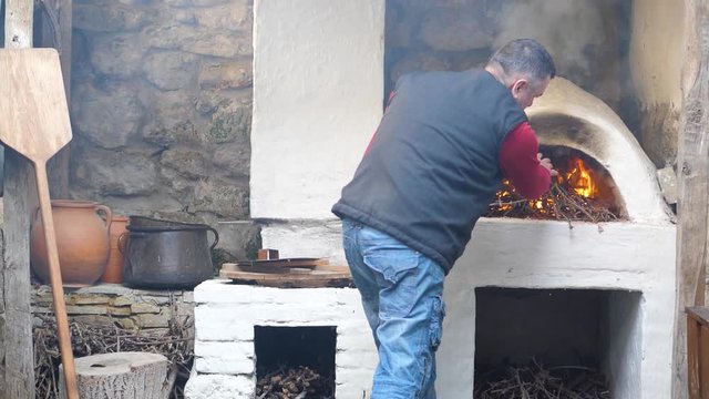 Man has melted the medieval stove, throwing the firewood to bake bread. 