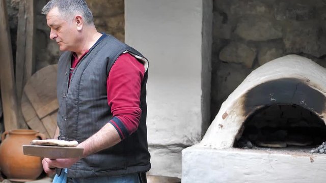 The Baker took the baked flatbread out of the oven with a wooden spatula