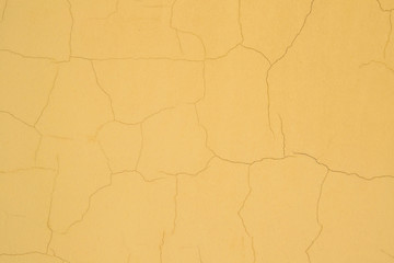 A dark yellow, plastered painted background with several small, subtle cracks. Old vintage orange surface. Cracked plaster