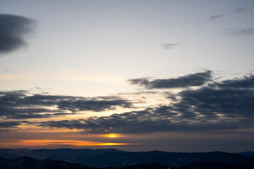 sun hiding behind clouds at sunrise in winter mountains, slovakia low tatras, dumbier
