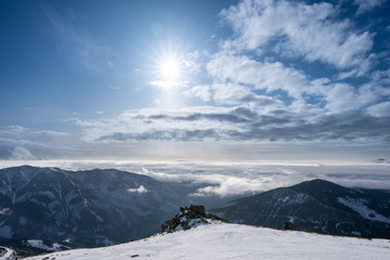 Snow covered mountains with clouds and sun with fog in valley, Slovakia Low Tatras Dumbier