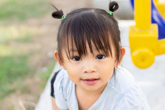 Portrait image of 1-2 years old baby. Happy Asian child girl smiling and relaxing at the garden park. Pretty girl wearing a white shirt. Summer season. Kids and healthy concept.