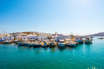 Fototapeta na wymiar Fishboats and yachts moored in Naoussa port, Paros island, Greece. View on dock for boats and yachts at bright sunny day