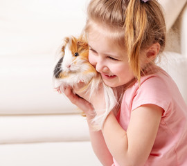 Cute little girk having a lot of fun with peruvian guinea pig