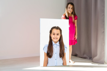 A happy little girl holds canvas at home