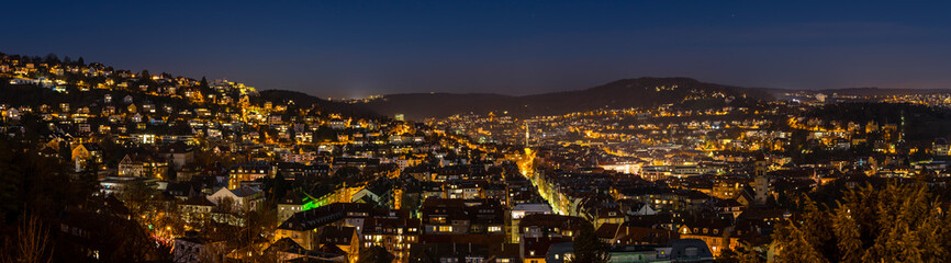 Germany, XXL panorama of magical city stuttgart, houses, churches, and skyline of illuminated buildings from above by night with full moon moonlight