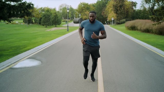 Yog man running on road. Afro sportsman training in park alone