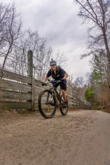 Fototapeta na wymiar mountain biker on bridle path in umstead state park, raleigh NC. a wet cloudy day means the singletrack trails are closed so many cyclists take to the dual track of the park to enjoy the outdoors.