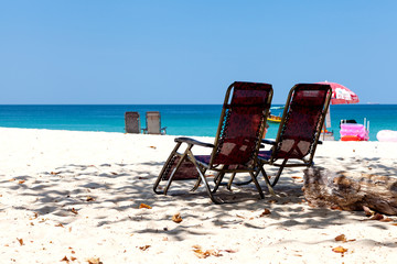 Beach chairs on the colorful and beautiful sand near the blue sea.