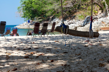 Swing on the beach by the sea. Sand, rope, log. Rest and relaxation.