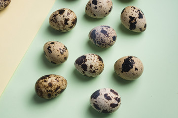 Fototapeta premium heap of quail eggs on yellow and green background. Vegetarian organic eco food. Top view. flatlay