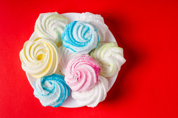 Homemade sweet colored meringue on red background.  .Dessert.