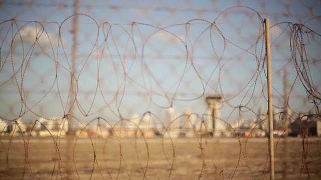 Airport control tower, focus pull to barbed wire electric motion security fence