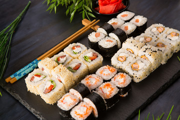 Set of sushi rolls with wasabi and ginger on a black background. Japanese oriental cuisine
