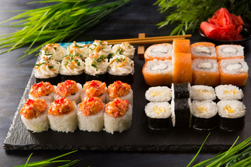 Set of sushi rolls with wasabi and ginger on a black background. Japanese oriental cuisine