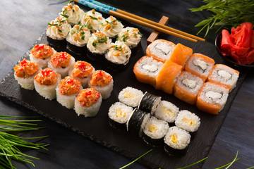 Set of sushi rolls with wasabi and ginger on a black background. Japanese oriental cuisine