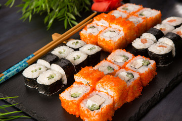 Set of sushi rolls with wasabi and ginger on a black background. Japanese oriental cuisine