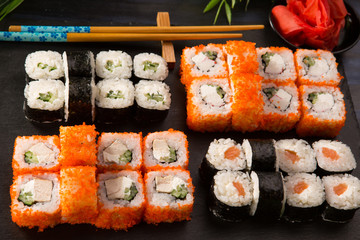 Set of sushi rolls with wasabi and ginger on a black background. Japanese oriental cuisine