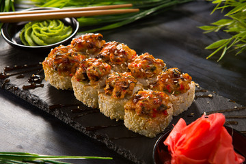 Set of baked sushi rolls with wasabi and ginger on a black background. Japanese oriental cuisine