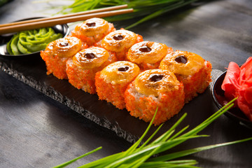 Set of baked sushi rolls with wasabi and ginger on a black background. Japanese oriental cuisine