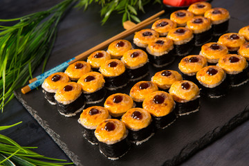 Set of baked sushi rolls with wasabi and ginger on a black background. Japanese oriental cuisine