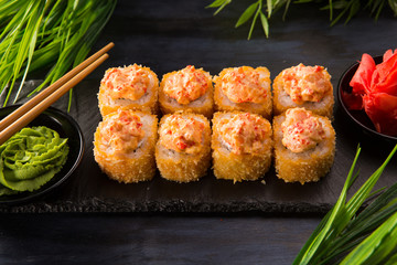 Set of baked sushi rolls with wasabi and ginger on a black background. Japanese oriental cuisine