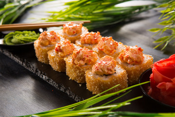 Set of baked sushi rolls with wasabi and ginger on a black background. Japanese oriental cuisine