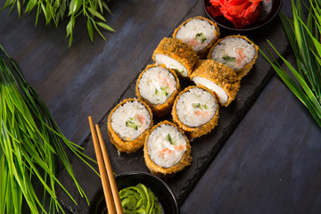 Set of baked sushi rolls with wasabi and ginger on a black background. Japanese oriental cuisine