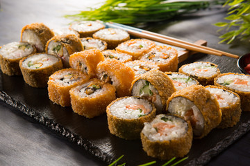Set of baked sushi rolls with wasabi and ginger on a black background. Japanese oriental cuisine