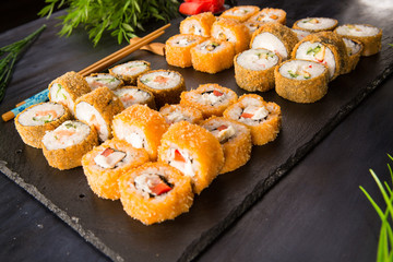 Set of baked sushi rolls with wasabi and ginger on a black background. Japanese oriental cuisine