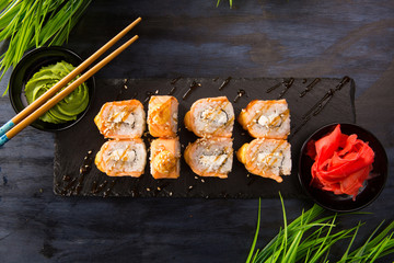 Set of baked sushi rolls with wasabi and ginger on a black background. Japanese oriental cuisine