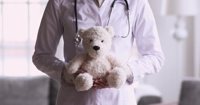 Woman paediatrician holding teddy bear toy, close up view