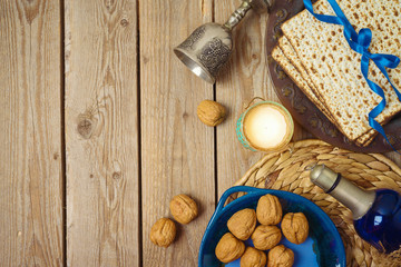 Jewish holiday Passover background with matzo, seder plate and wine on wooden table.
