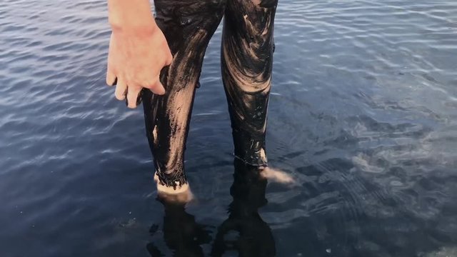 Young woman Making Body Healthy Skin Mask with Black Medical Mud at the Lake of Salty Water.