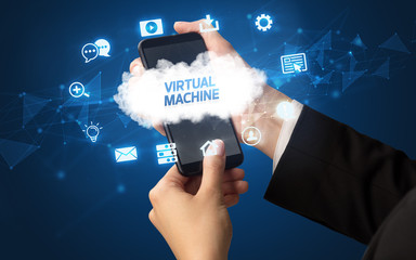 Female hand holding smartphone with VIRTUAL MACHINE inscription, cloud technology concept