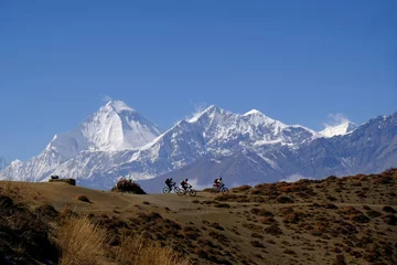 Photo sur Plexiglas Dhaulagiri Groupe de motards dans les montagnes avec la chaîne enneigée du Dhaulagiri en arrière-plan, Himalaya, Mustang Land, Népal. Rencontre lors d& 39 un trekking autour des Annapurna