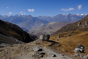 Mountain views with a boulder in the foreground on the trail from the Thorong La Pass to Muktinath in Mustang Land, Himalayas, Nepal. During trekking around Annapurna, Annapurna Ciruit