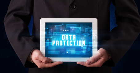 Young business person working on tablet and shows the digital sign: DATA PROTECTION
